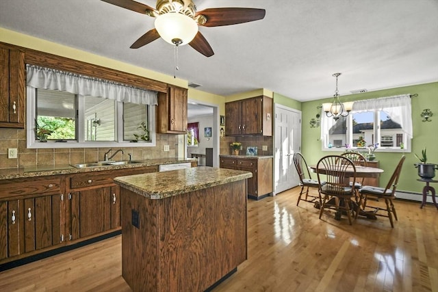 kitchen featuring a sink, tasteful backsplash, a kitchen island, light wood-style flooring, and a ceiling fan