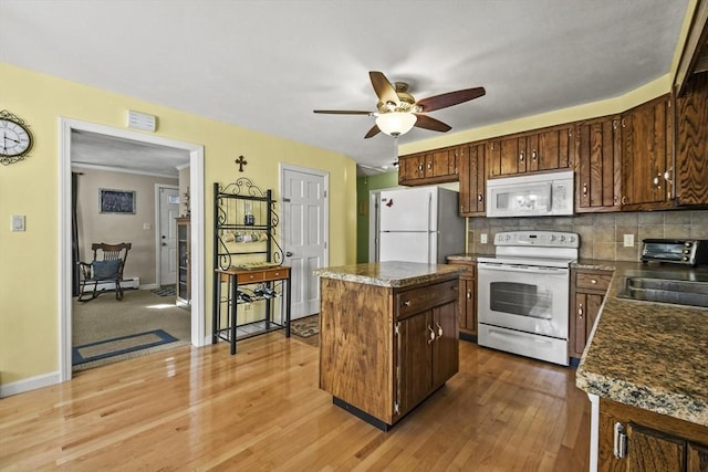 kitchen featuring white appliances, a center island, ceiling fan, decorative backsplash, and a sink