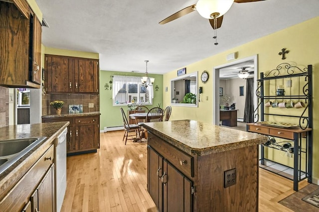 kitchen with ceiling fan, light wood-style floors, a center island, decorative backsplash, and dishwashing machine