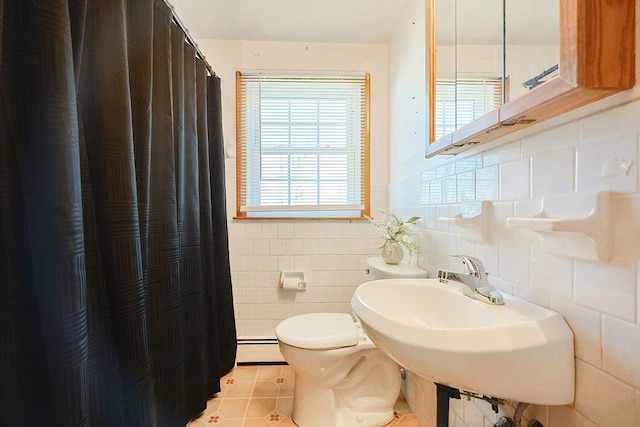 full bath featuring tile walls, toilet, baseboard heating, a sink, and tile patterned flooring