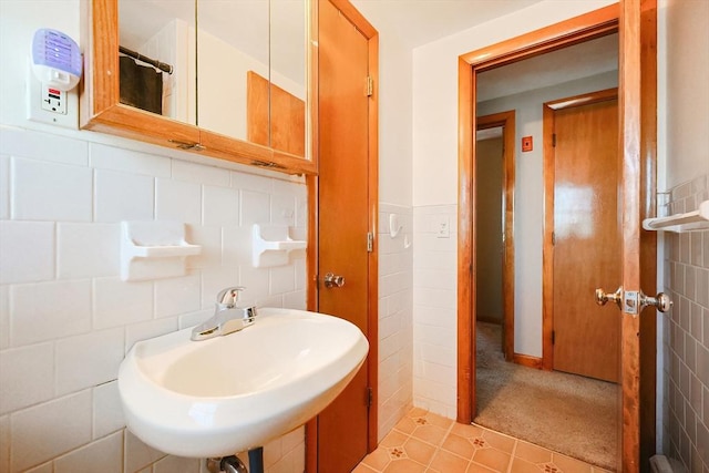 bathroom with a sink, a wainscoted wall, and tile walls