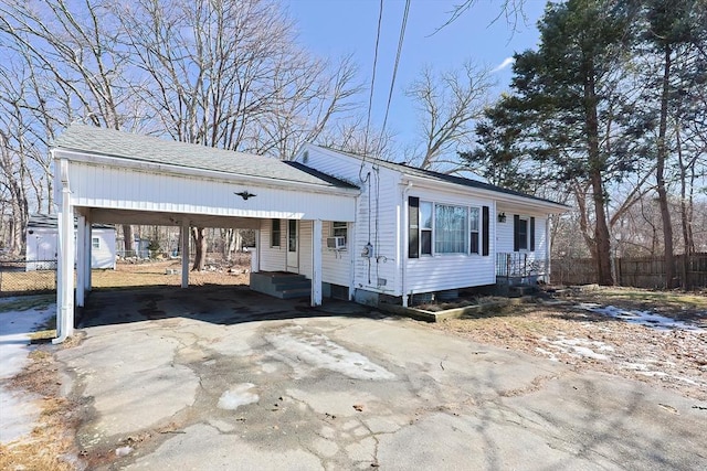 view of front of house with entry steps, driveway, a carport, and fence