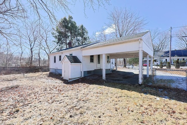 exterior space featuring a chimney, fence, and a carport