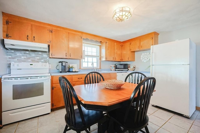 kitchen with white appliances, light countertops, under cabinet range hood, and light tile patterned floors