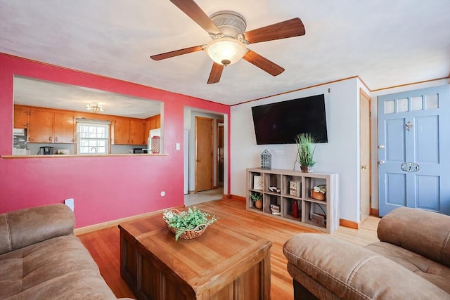 living area featuring light wood finished floors, baseboards, and a ceiling fan