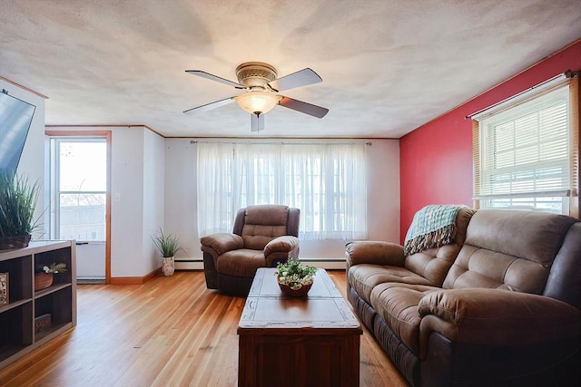 living room with light wood-style floors, a baseboard radiator, baseboards, and a ceiling fan