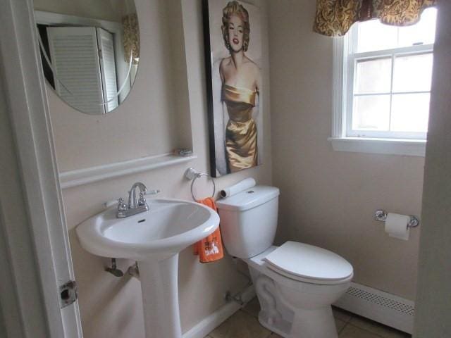 half bathroom with tile patterned floors, baseboard heating, and toilet