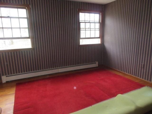 spare room featuring plenty of natural light, a baseboard radiator, and wood finished floors