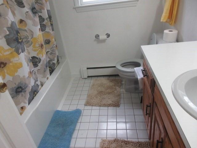 full bathroom with vanity, toilet, baseboard heating, tile patterned floors, and shower / tub combo