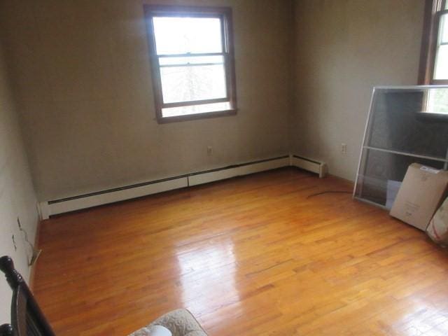 empty room featuring a baseboard radiator and light wood-type flooring