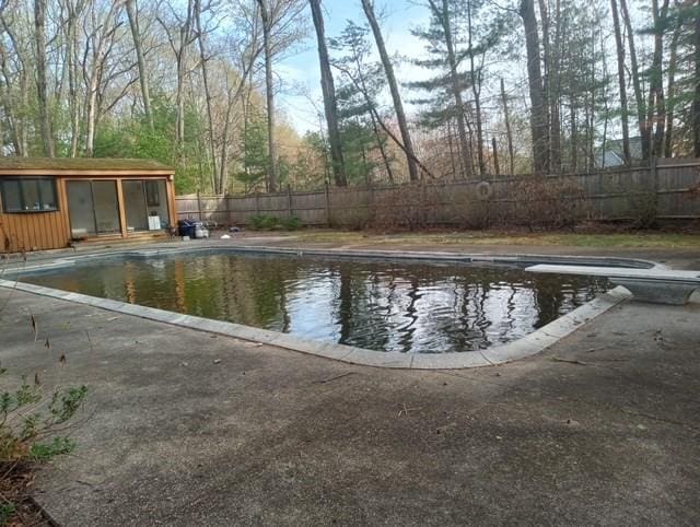 view of swimming pool featuring a fenced in pool, an outbuilding, a fenced backyard, and a patio area
