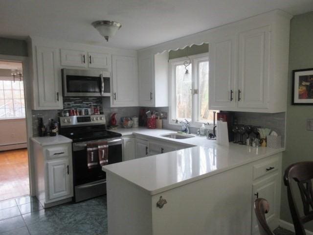 kitchen featuring backsplash, stainless steel appliances, a sink, and light countertops