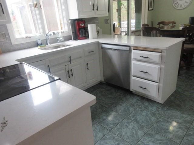 kitchen featuring a sink, stainless steel dishwasher, a peninsula, and white cabinetry