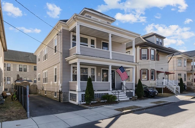 traditional style home featuring a balcony, a porch, and a gate