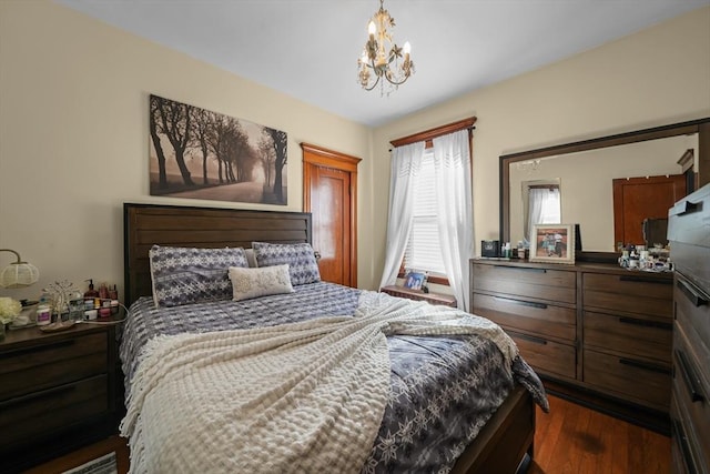 bedroom featuring an inviting chandelier and dark wood finished floors