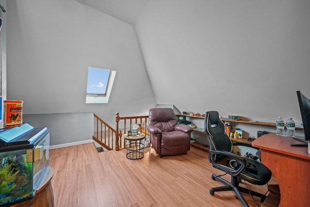 office area with vaulted ceiling with skylight, baseboards, and wood finished floors