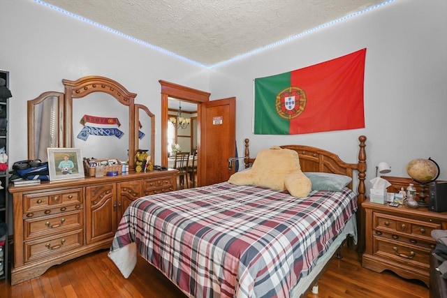 bedroom with a chandelier, a textured ceiling, and wood-type flooring