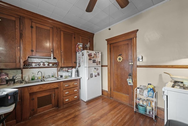 kitchen with backsplash, light countertops, dark wood-style floors, white appliances, and a sink