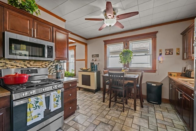 kitchen with decorative backsplash, stainless steel appliances, crown molding, and ceiling fan