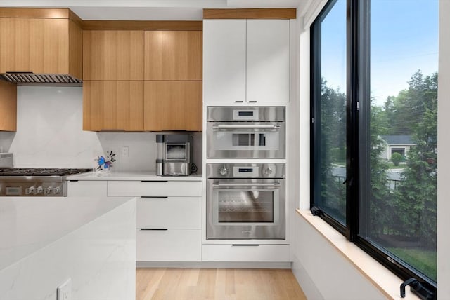 1242 Beacon St, Newton, MA 02468 - kitchen featuring light countertops, double oven, modern cabinets, backsplash, and white cabinetry