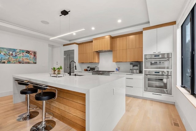 1242 Beacon St, Newton, MA 02468 - kitchen featuring modern cabinets, appliances with stainless steel finishes, light wood-type flooring, light countertops, and recessed lighting