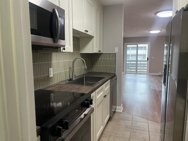 kitchen with stainless steel appliances, a sink, tasteful backsplash, and baseboards