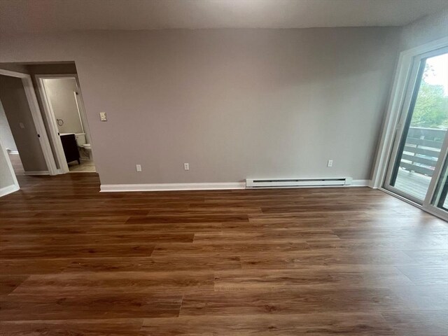 spare room featuring baseboard heating, dark wood-type flooring, and baseboards
