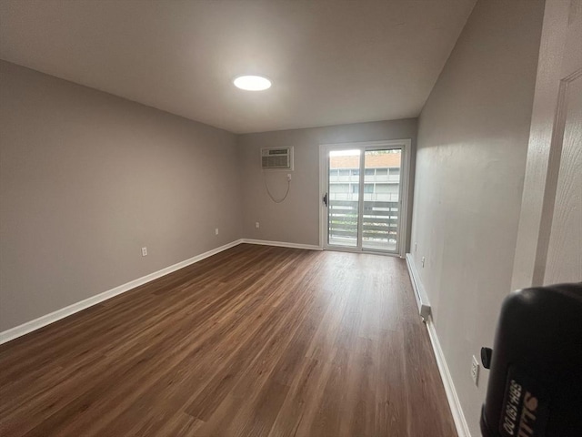 unfurnished room featuring dark wood-style floors, baseboards, and an AC wall unit