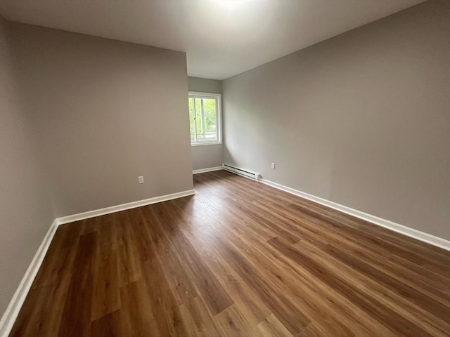 empty room with a baseboard radiator, dark wood finished floors, and baseboards