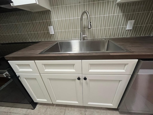 kitchen view of a sink, backsplash, dishwasher, and white cabinets