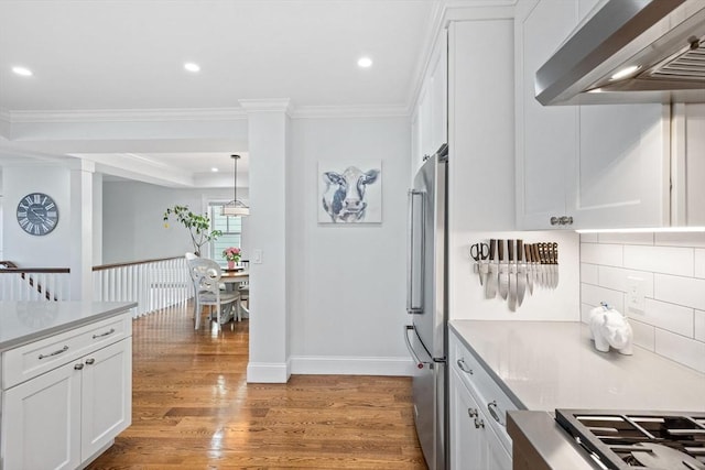 kitchen featuring wall chimney range hood, gas cooktop, light wood-type flooring, light countertops, and white cabinetry
