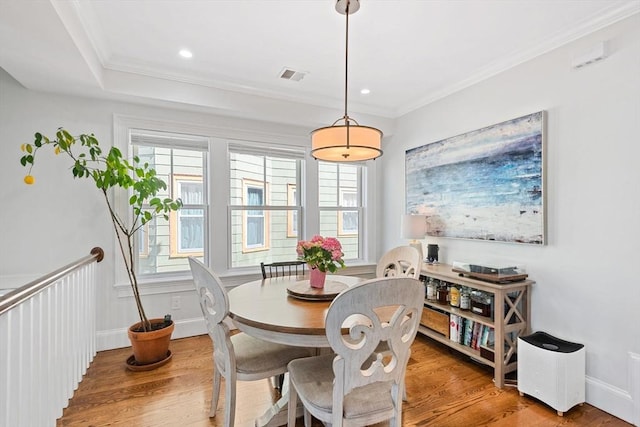 dining space with crown molding, visible vents, and wood finished floors