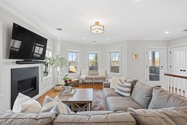 living area featuring recessed lighting, crown molding, a glass covered fireplace, and wood finished floors