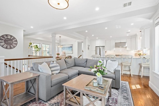 living area with recessed lighting, visible vents, ornamental molding, and light wood finished floors