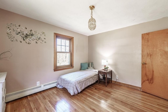 bedroom featuring baseboards, a baseboard heating unit, and light wood-style flooring