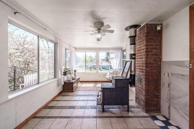 sunroom featuring baseboards and a wood stove