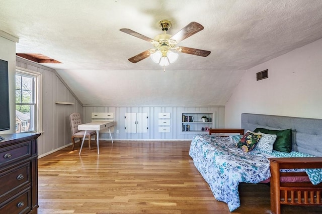 bedroom featuring a textured ceiling, visible vents, lofted ceiling, and light wood-type flooring