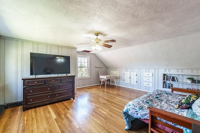 bedroom with a textured ceiling, light wood finished floors, a ceiling fan, and vaulted ceiling