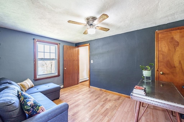 living room with light wood-style flooring, a textured ceiling, ceiling fan, and a baseboard heating unit
