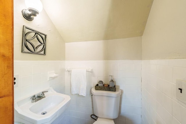 bathroom featuring a wainscoted wall, lofted ceiling, toilet, and tile walls