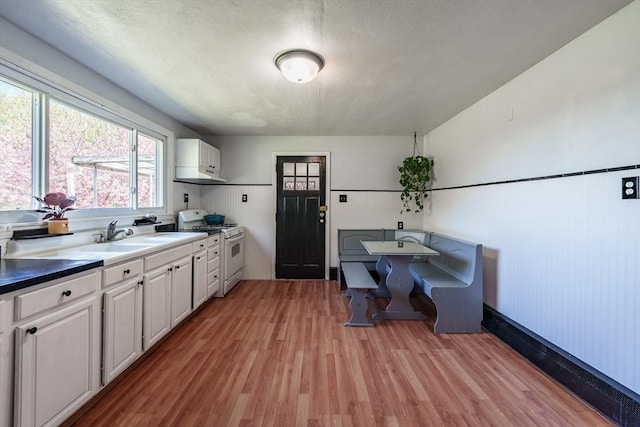 kitchen with white cabinets, white range with gas stovetop, and light wood-type flooring