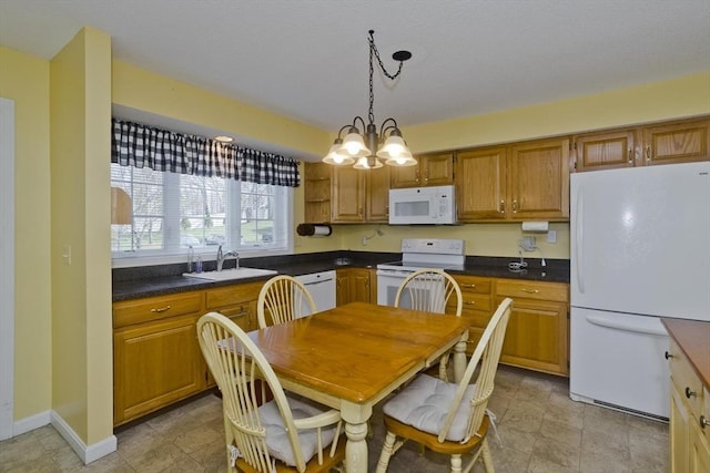 585 Sheridan St Unit 36, Chicopee, MA 01020 - kitchen with a sink, dark countertops, white appliances, brown cabinets, and hanging light fixtures
