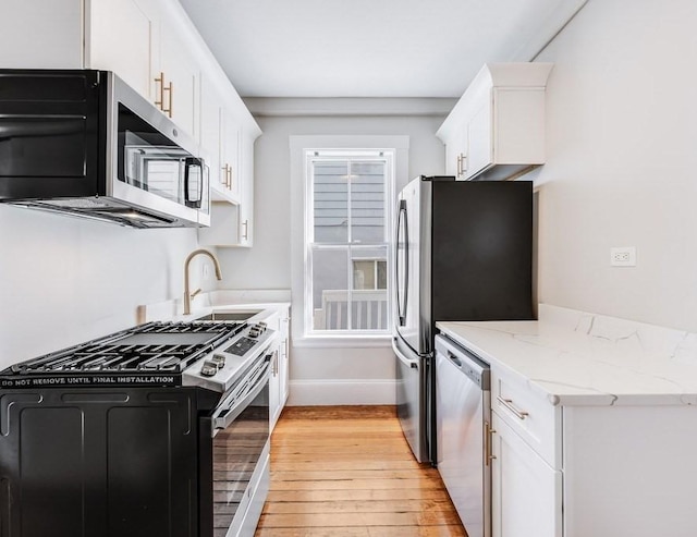 52-54 Bonair St, Somerville, MA 02145 - kitchen with appliances with stainless steel finishes, light wood-style flooring, white cabinets, and light stone countertops