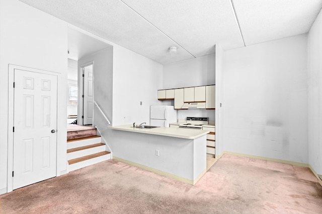 kitchen featuring white appliances, a textured ceiling, light carpet, and kitchen peninsula