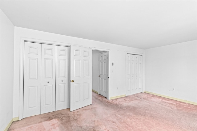 unfurnished bedroom with two closets and carpet floors