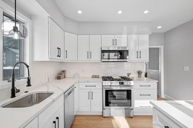 kitchen featuring white cabinetry, stainless steel appliances, decorative light fixtures, and sink