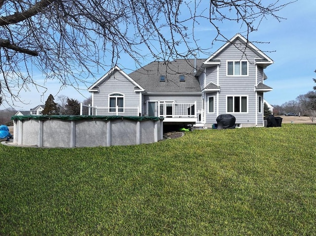 back of house featuring a covered pool, a lawn, and roof with shingles