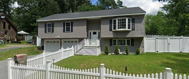 split foyer home featuring an attached garage, driveway, a gate, and view of scattered trees