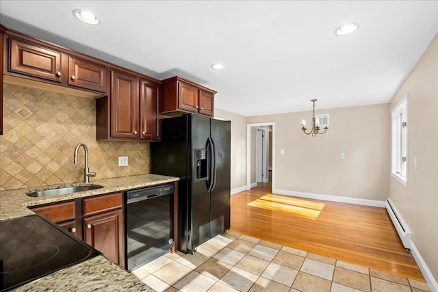 kitchen with black appliances, light stone countertops, sink, a baseboard radiator, and decorative backsplash