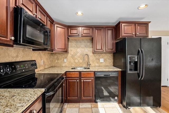 kitchen with sink, black appliances, light stone countertops, and decorative backsplash